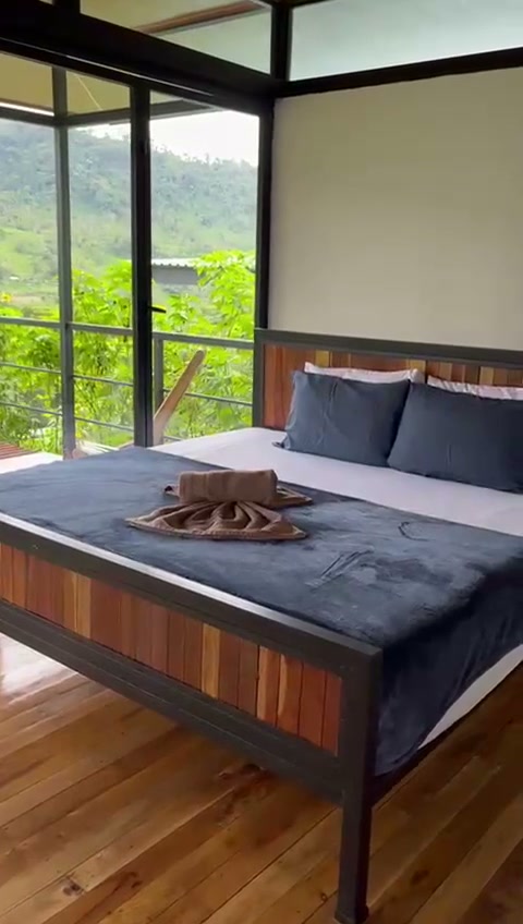 Interior de cabaña con cama de madera y vista a la montaña